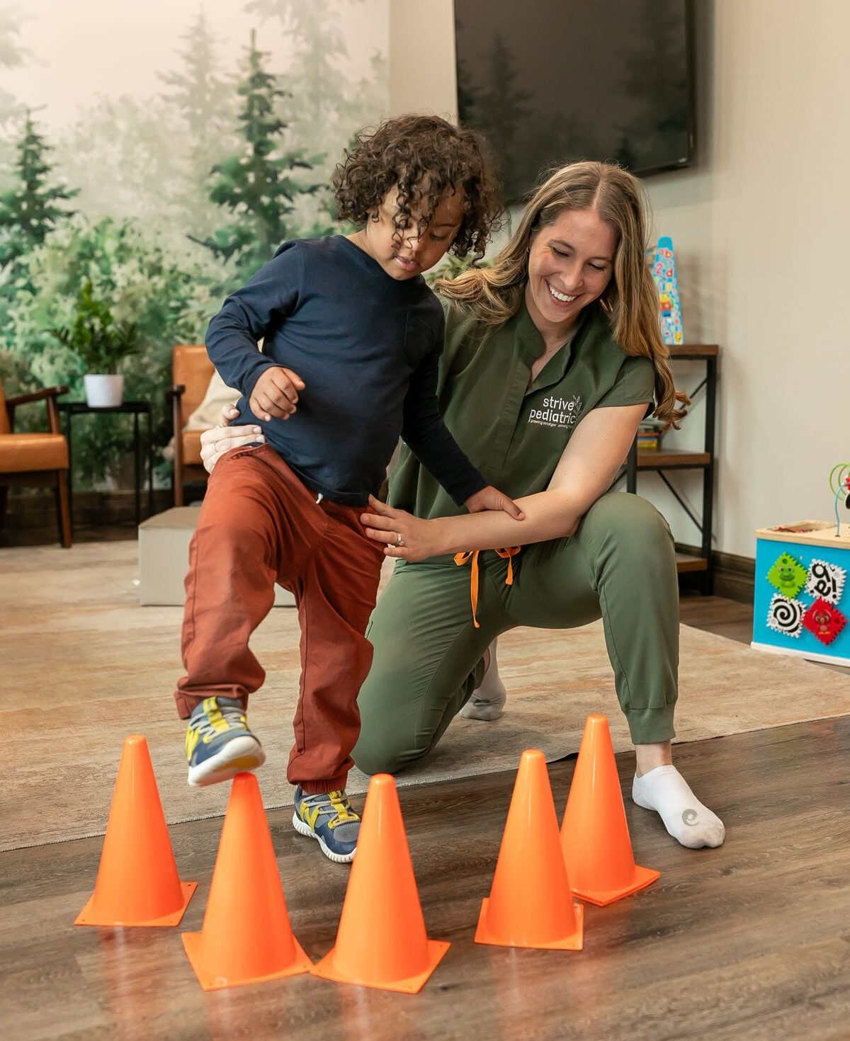 A nurse helping a toddler patient through Physical therapy using cones